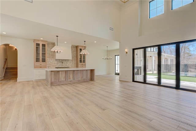 789 Old Mill Ct, Ball Ground, GA 30107 - kitchen with arched walkways, light wood finished floors, light countertops, glass insert cabinets, and open floor plan