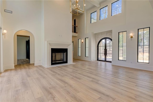789 Old Mill Ct, Ball Ground, GA 30107 - unfurnished living room featuring a high ceiling, light wood-style flooring, a fireplace, arched walkways, and baseboards