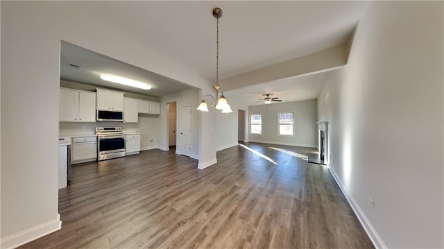 kitchen with hanging light fixtures, hardwood / wood-style floors, white cabinets, ceiling fan with notable chandelier, and appliances with stainless steel finishes