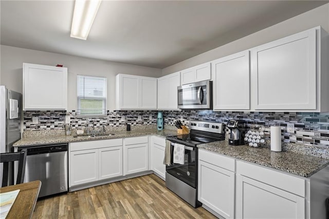 kitchen with white cabinetry, sink, stone countertops, and appliances with stainless steel finishes