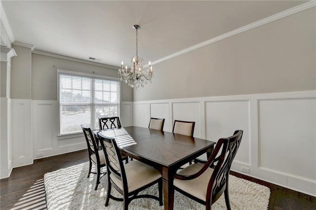 dining room featuring a chandelier, crown molding, and dark wood-type flooring