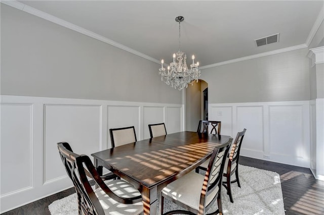 dining room with a chandelier, dark wood-type flooring, and ornamental molding