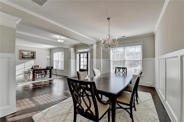 dining space with a notable chandelier, ornamental molding, dark wood-type flooring, and ornate columns