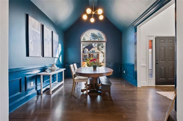 dining room featuring lofted ceiling, an inviting chandelier, dark wood finished floors, and a wainscoted wall