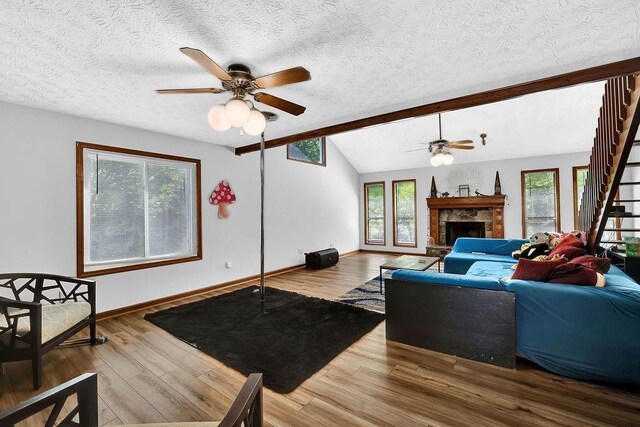 2775 Whippoorwill Cir, Duluth, GA 30097 - living room with a ceiling fan, a textured ceiling, wood finished floors, and a stone fireplace