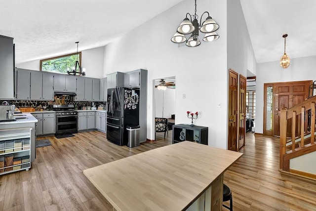 2775 Whippoorwill Cir, Duluth, GA 30097 - kitchen with a chandelier, double oven range, gray cabinetry, black fridge with ice dispenser, and high vaulted ceiling