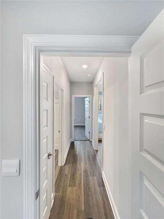 corridor featuring baseboards and dark wood finished floors