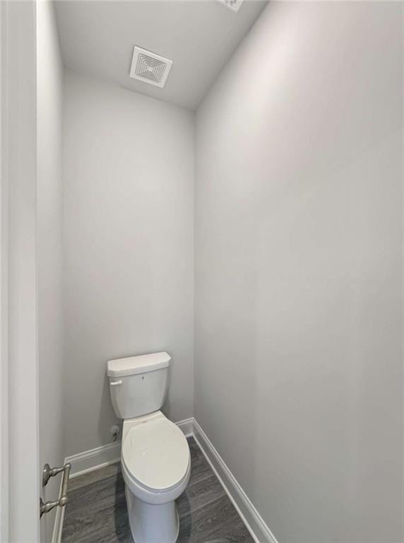 bathroom with visible vents, toilet, baseboards, and wood finished floors