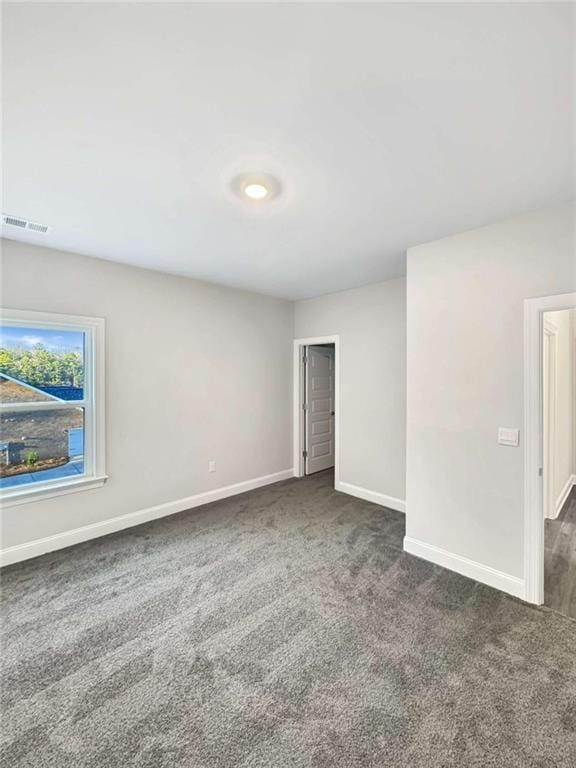 carpeted spare room featuring visible vents and baseboards