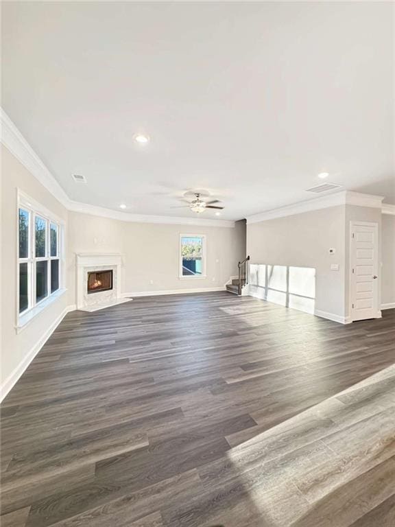 unfurnished living room featuring a premium fireplace, a ceiling fan, baseboards, ornamental molding, and dark wood-style floors