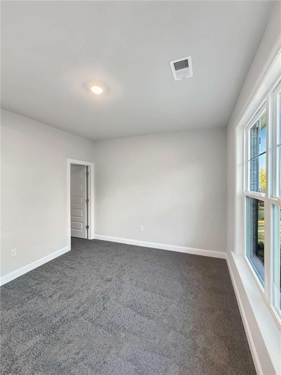 unfurnished room featuring baseboards, visible vents, and dark colored carpet