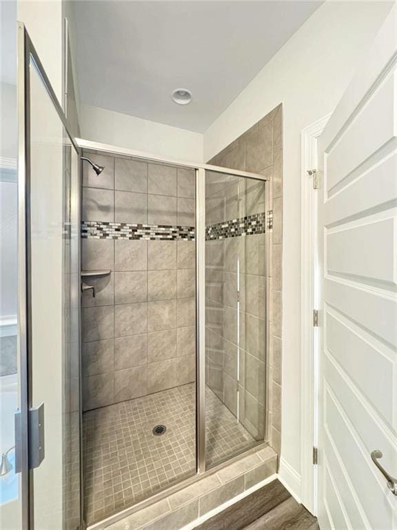 bathroom featuring wood finished floors and a shower stall