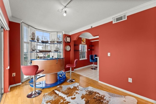 interior space with ornamental molding, rail lighting, light tile patterned floors, and a textured ceiling