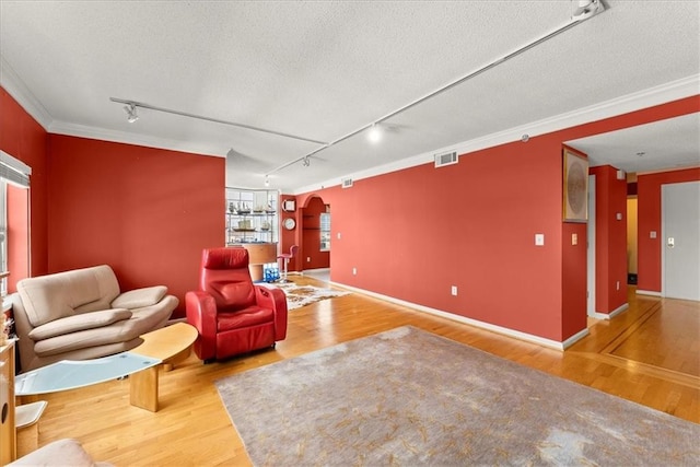 living room featuring crown molding, rail lighting, a textured ceiling, and hardwood / wood-style flooring