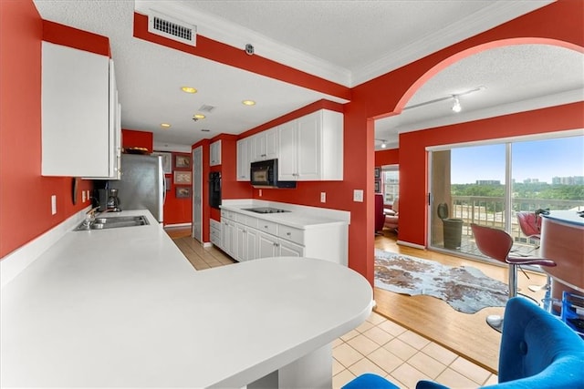 kitchen featuring white cabinets, stovetop, sink, light tile patterned floors, and a textured ceiling