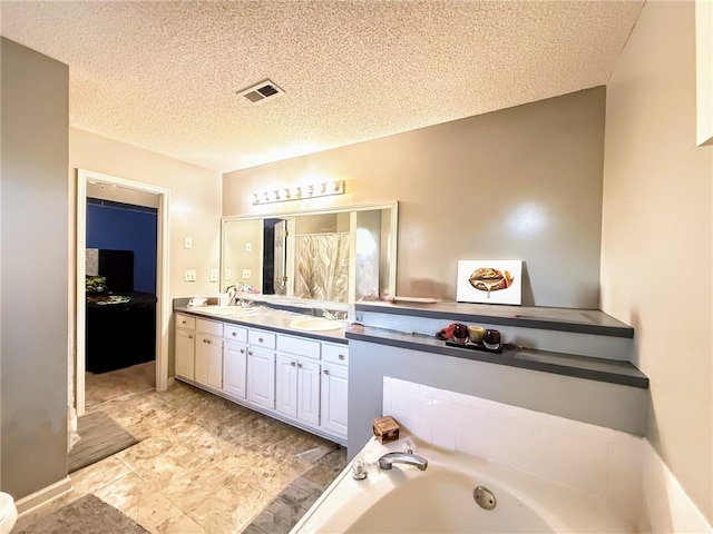 bathroom featuring a bath, vanity, and a textured ceiling