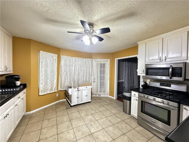 kitchen featuring ceiling fan, stainless steel appliances, light tile patterned flooring, a textured ceiling, and white cabinets