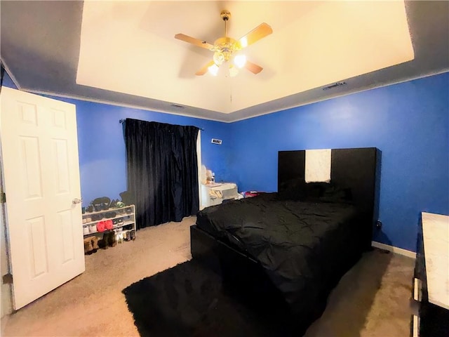 bedroom with ceiling fan, a tray ceiling, and carpet flooring