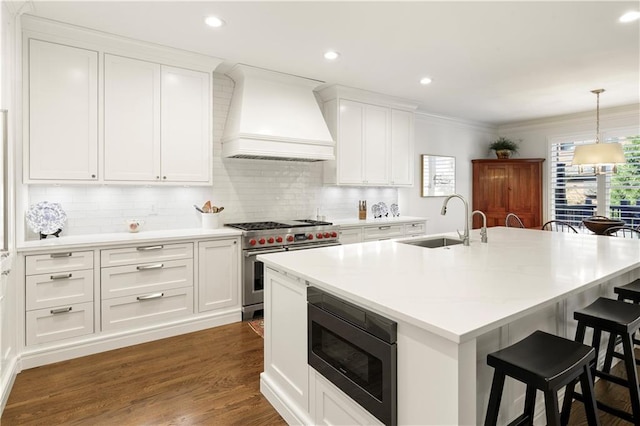 kitchen with a breakfast bar, white cabinets, high end stainless steel range oven, built in microwave, and custom range hood