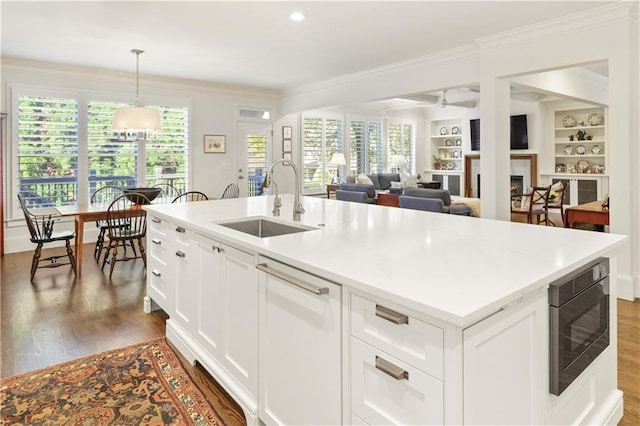 kitchen featuring black microwave, a fireplace, a sink, ornamental molding, and plenty of natural light