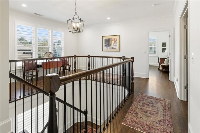 hall featuring ornamental molding, a wealth of natural light, and an upstairs landing