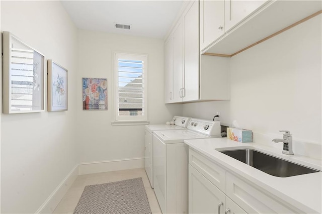 laundry room featuring washing machine and clothes dryer, cabinet space, visible vents, a sink, and baseboards