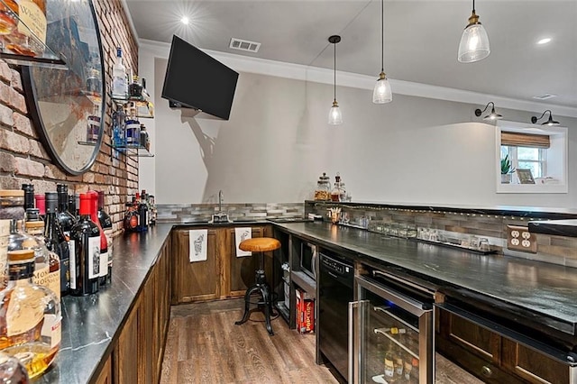 bar with tasteful backsplash, visible vents, ornamental molding, wood finished floors, and indoor wet bar