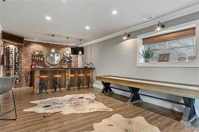 bar with crown molding, a dry bar, visible vents, brick wall, and wood finished floors