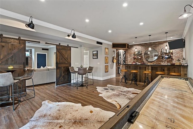 game room with brick wall, a barn door, a dry bar, and crown molding