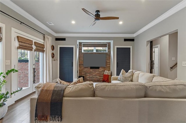 living area featuring a ceiling fan, visible vents, crown molding, and wood finished floors