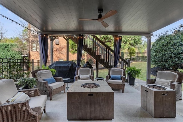 view of patio featuring a ceiling fan, an outdoor living space with a fire pit, fence, and stairway