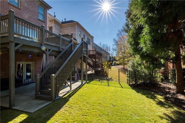 view of yard featuring a wooden deck, a patio, a fenced backyard, stairs, and french doors