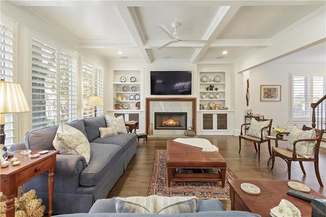 living area with built in shelves, a premium fireplace, coffered ceiling, wood finished floors, and beamed ceiling