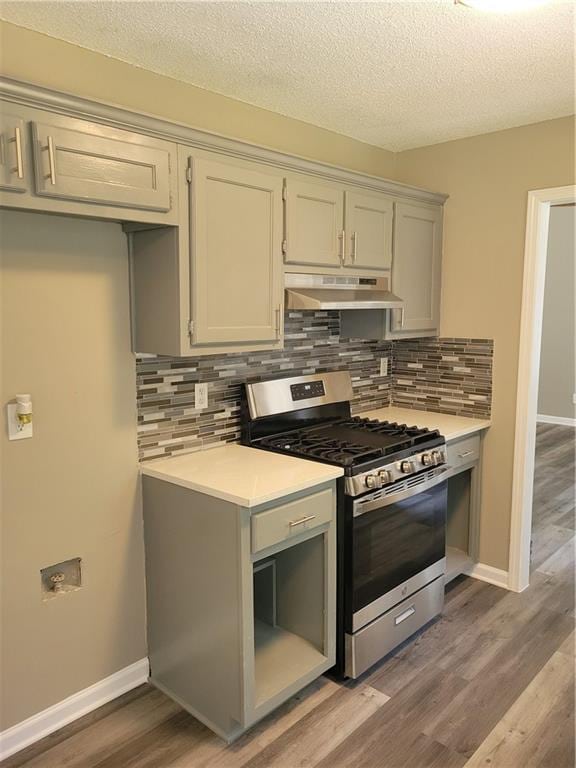 kitchen with backsplash, stainless steel gas range oven, wood-type flooring, and a textured ceiling