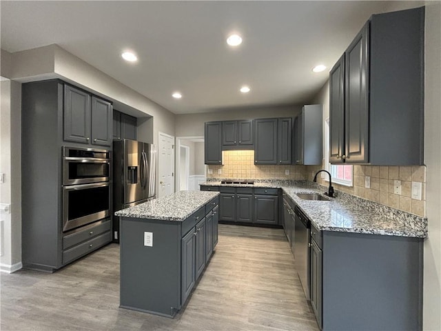 kitchen with a kitchen island, appliances with stainless steel finishes, sink, gray cabinetry, and light stone counters