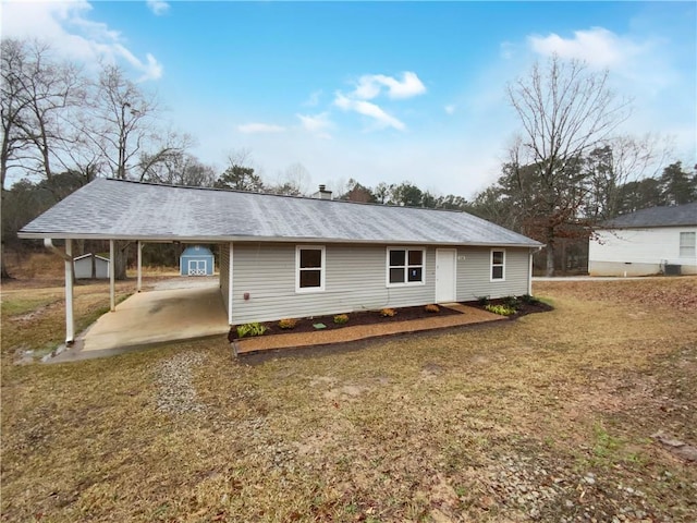 back of property with driveway, an attached carport, and a yard