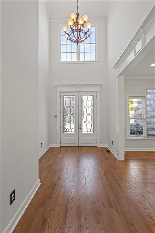 entryway featuring french doors, ornamental molding, a chandelier, and wood-type flooring