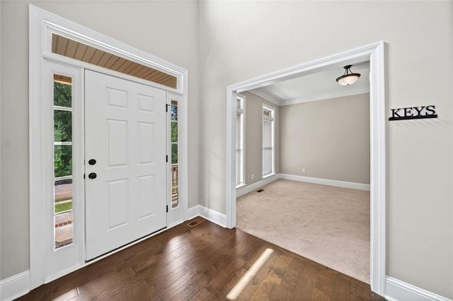 entrance foyer featuring ornamental molding, plenty of natural light, and dark hardwood / wood-style flooring