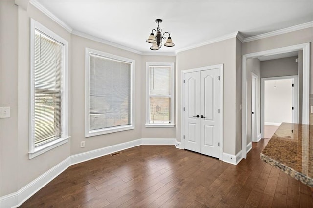 unfurnished bedroom with ornamental molding, an inviting chandelier, a closet, and dark hardwood / wood-style flooring