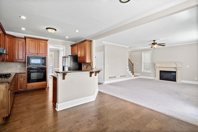 kitchen with ceiling fan, backsplash, black appliances, a kitchen breakfast bar, and dark hardwood / wood-style floors