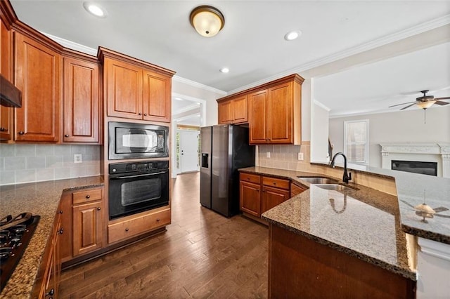 kitchen with dark stone counters, dark hardwood / wood-style floors, sink, black appliances, and ceiling fan