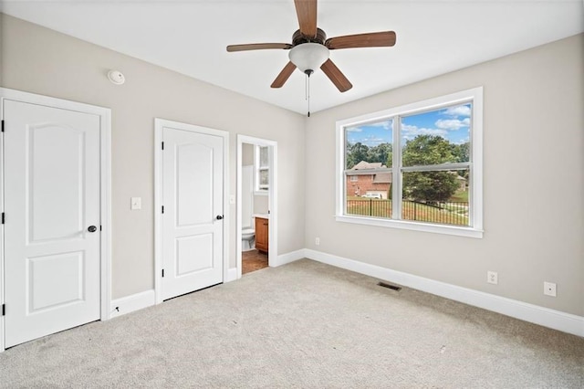 unfurnished bedroom with connected bathroom, carpet, and ceiling fan