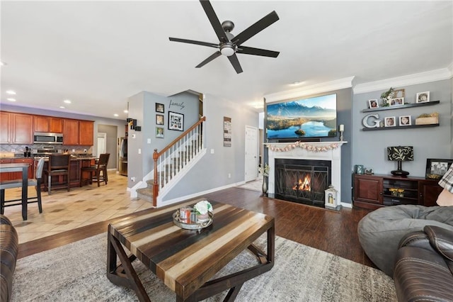 living room featuring light wood-type flooring, a warm lit fireplace, stairs, and baseboards