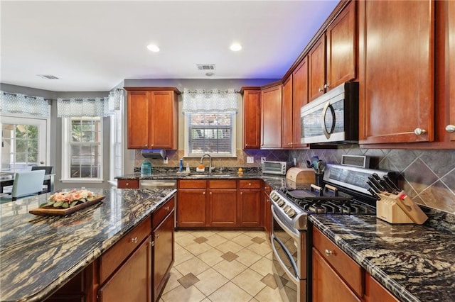 kitchen featuring stainless steel appliances, tasteful backsplash, visible vents, light tile patterned flooring, and a sink