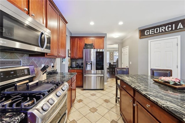 kitchen with light tile patterned floors, recessed lighting, appliances with stainless steel finishes, decorative backsplash, and dark stone counters