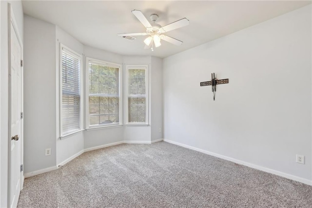 spare room featuring a ceiling fan, carpet, and baseboards