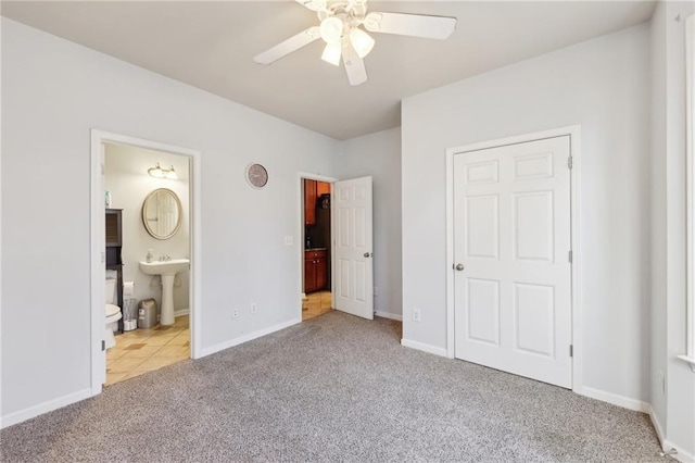 unfurnished bedroom featuring carpet floors, connected bathroom, a sink, and baseboards