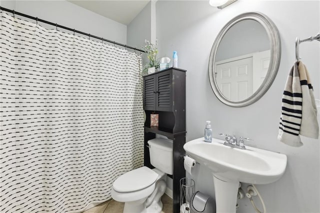 bathroom featuring toilet, curtained shower, and tile patterned floors