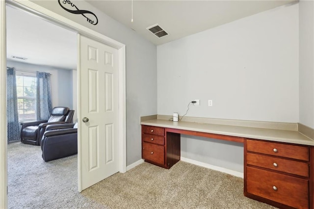 office area featuring visible vents, built in study area, and light colored carpet