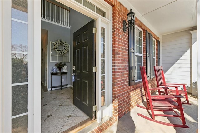 entrance to property featuring covered porch and brick siding